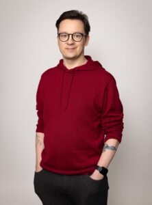 Muotokuva Mikosta seisomassa punaisessa hupparissa.