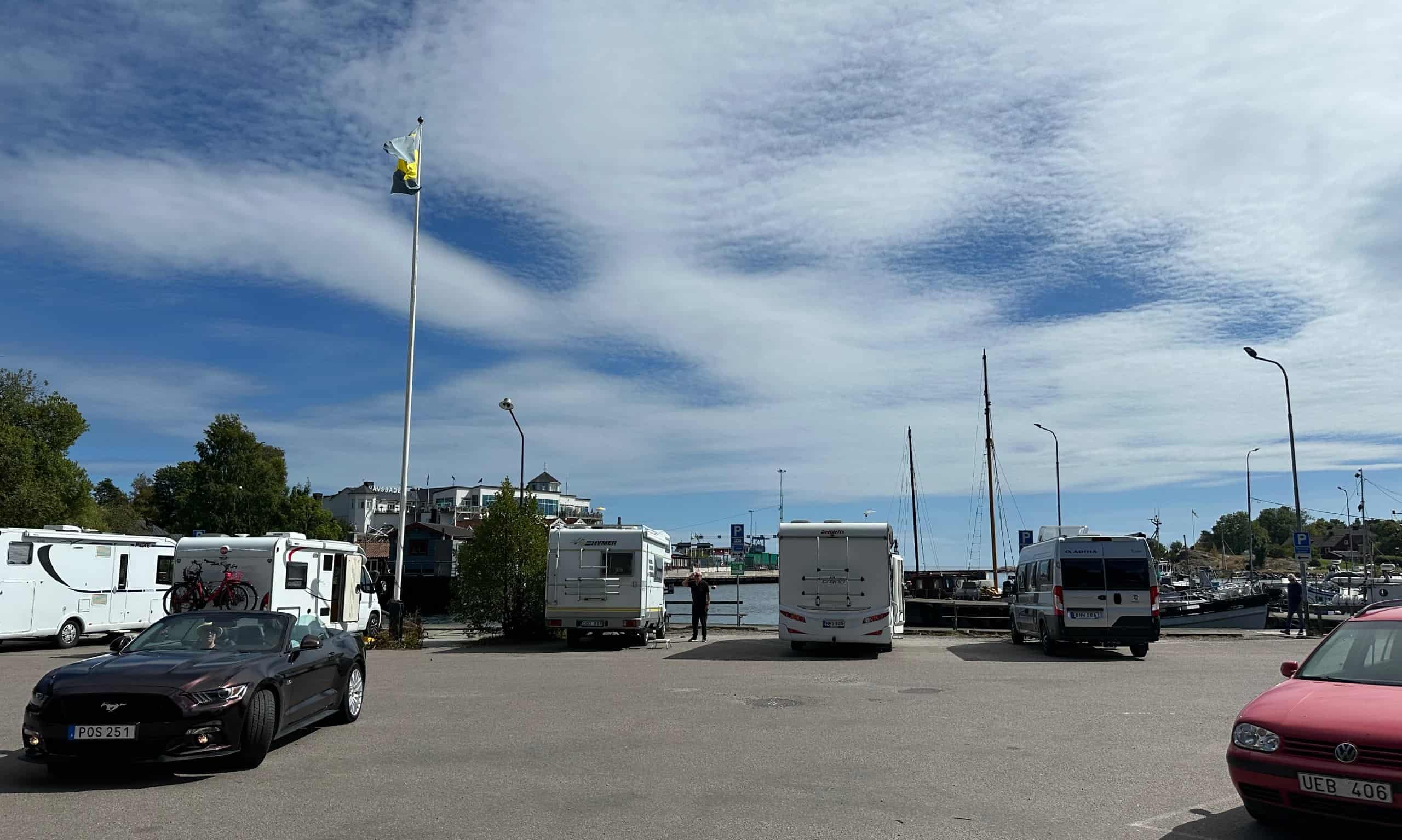 Grisslehamnin sataman parkkipaikka kesäisenä päivänä. Taustalla näkyy kylpylä.